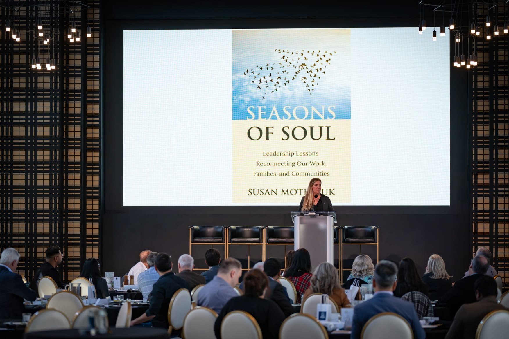 Susan Motkaluk at the lectern with the Seasons of Soul cover on screen